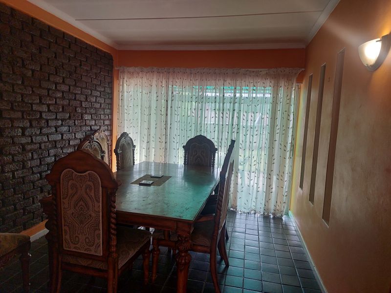 Dining room featuring an exposed brick accent wall, tiled flooring, and decorative wall niches, providing a distinct character to the space.