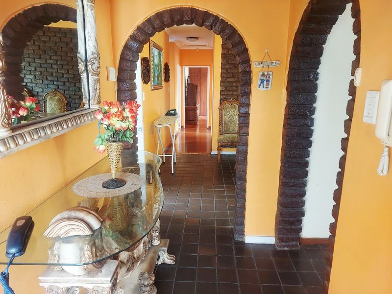 A hallway featuring distinctive brick archways and dark tiled flooring, connecting multiple living areas within the home.