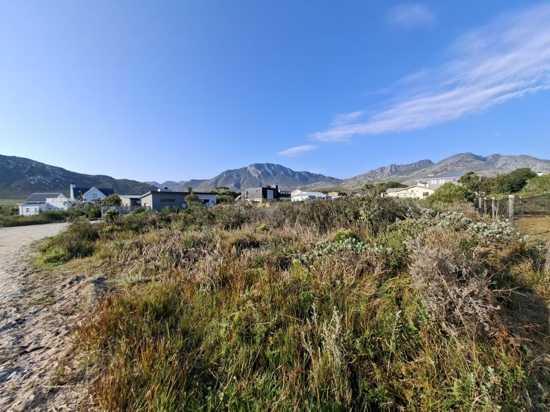 A wide-angle view of the vacant residential land featuring natural coastal vegetation with a scenic mountain range backdrop.