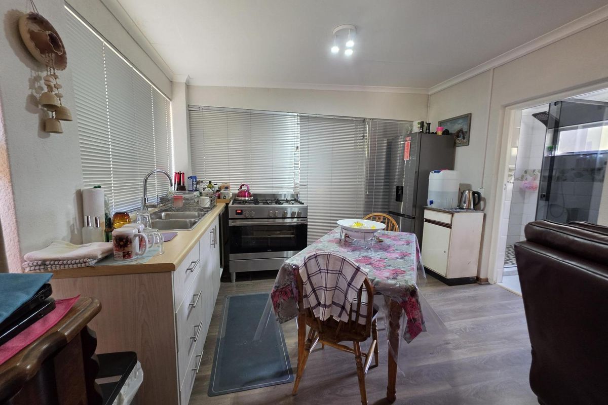 Functional kitchen featuring laminate cabinetry, stainless steel gas stove, double basin sink, and durable laminate flooring with ample natural light.