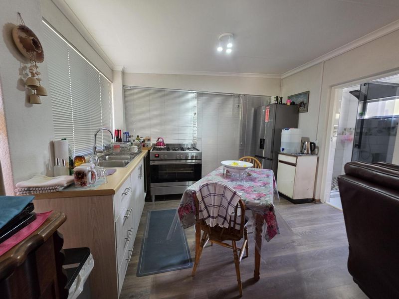 Functional kitchen featuring laminate cabinetry, stainless steel gas stove, double basin sink, and durable laminate flooring with ample natural light.