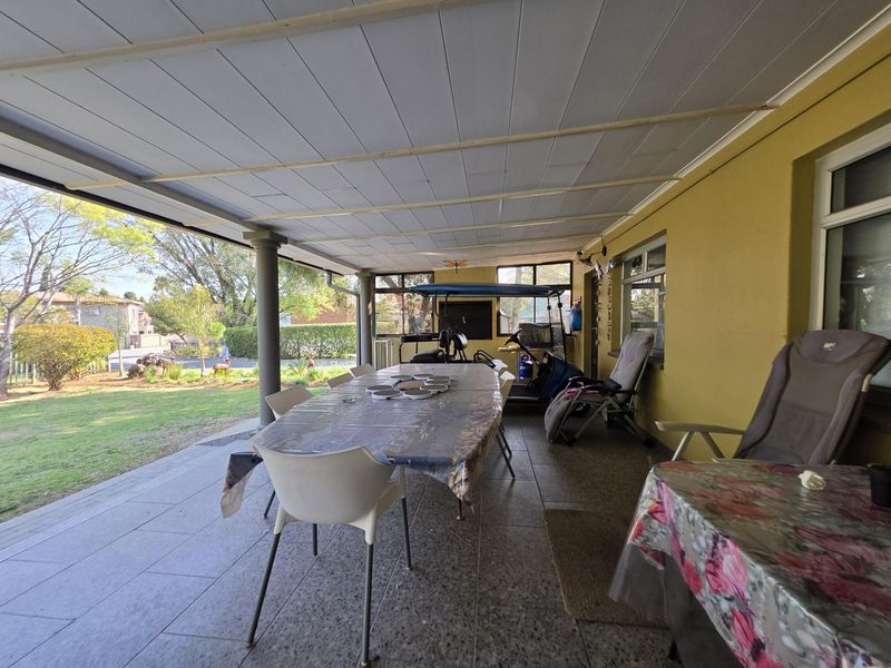 A spacious covered patio featuring tiled flooring and a panelled ceiling, overlooking the garden area.