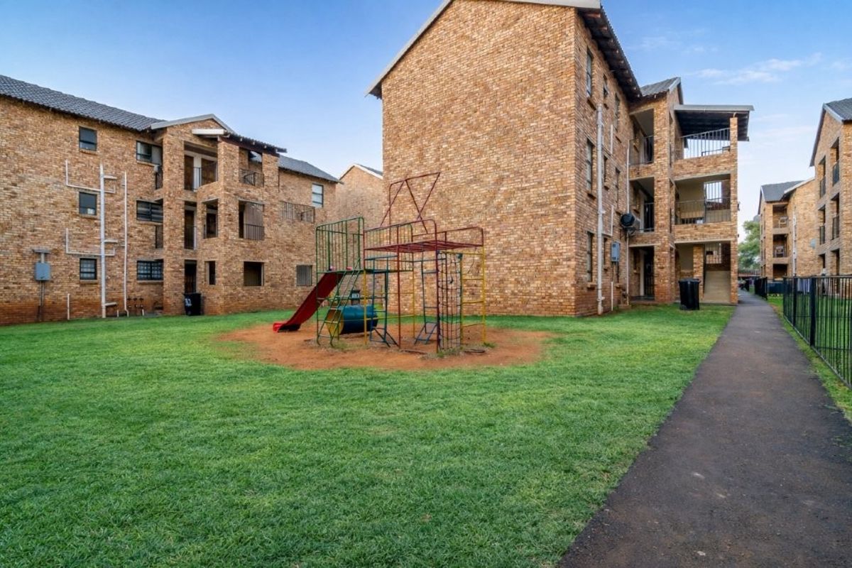 View of the apartment complex exterior featuring face brick facades, communal lawn areas, and a playground for residents.