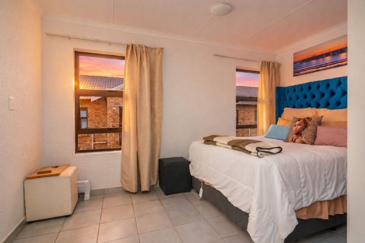 A bedroom featuring tiled flooring and dual windows with aluminium frames, offering a functional space with neutral wall finishes.