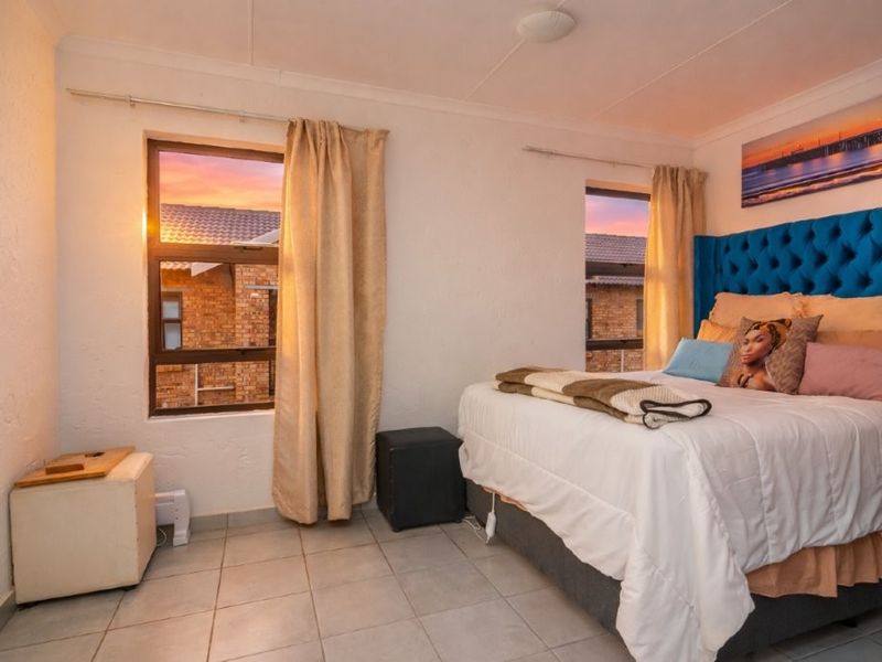 A bedroom featuring tiled flooring and dual windows with aluminium frames, offering a functional space with neutral wall finishes.