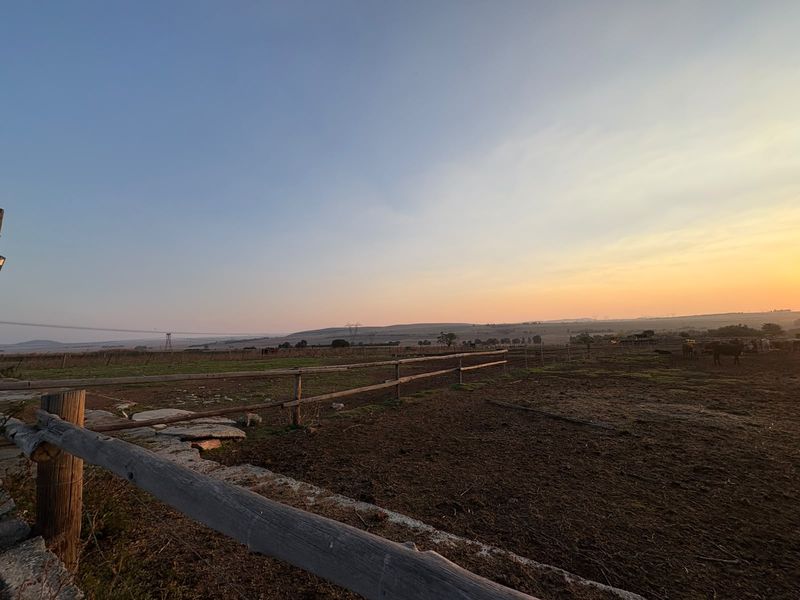 Expansive rural landscape view featuring traditional timber post and rail fencing at sunset.