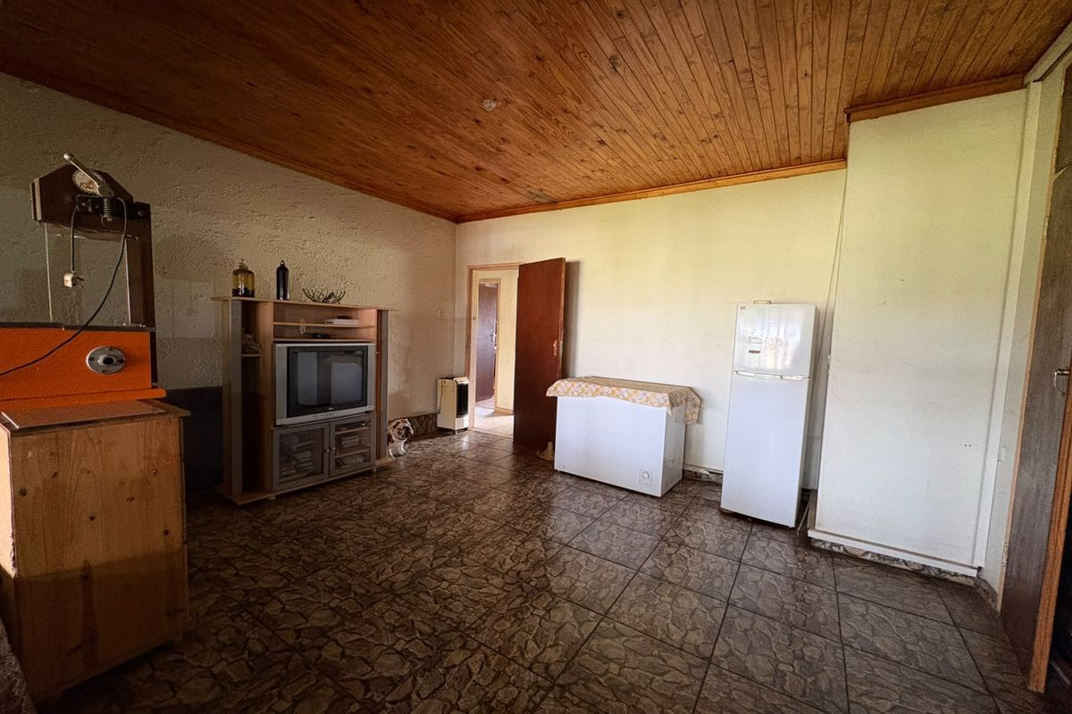 Living area featuring a timber tongue and groove ceiling and tiled flooring, offering a dated interior space ready for modernization.