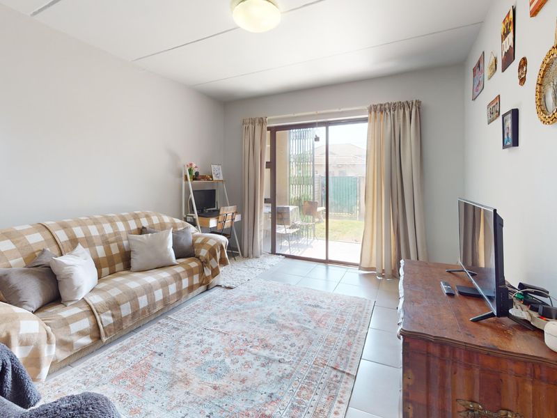 A bright living room featuring tiled flooring and a large sliding glass door providing direct access to the outdoor patio area.