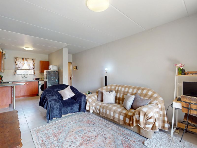 An open-plan living and kitchen area featuring tiled flooring, functional cabinetry, and a combined layout suitable for modern apartment living.
