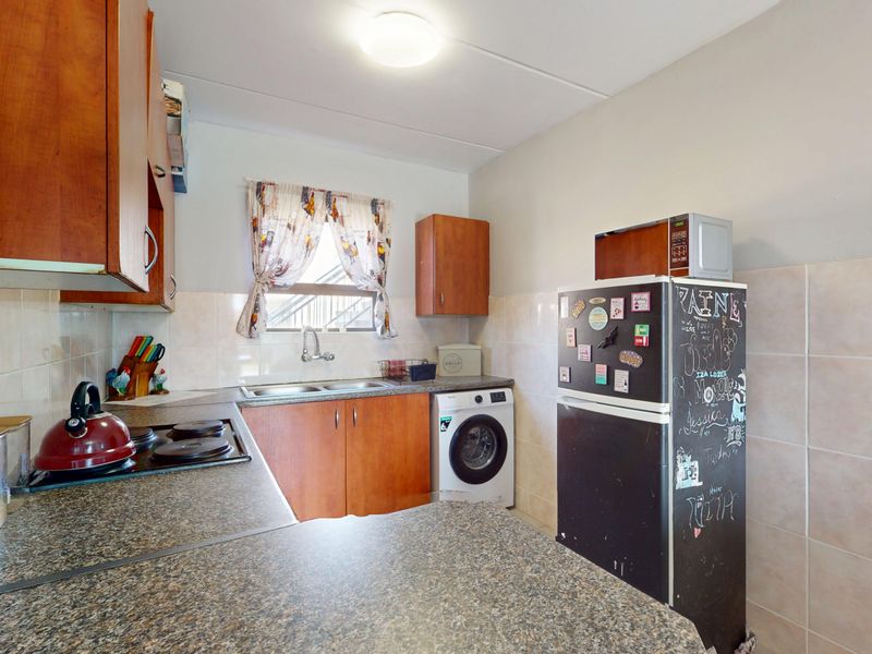 Functional kitchen featuring laminate countertops, built-in cabinetry, a double basin sink, and an electric hob with tiled splashback.