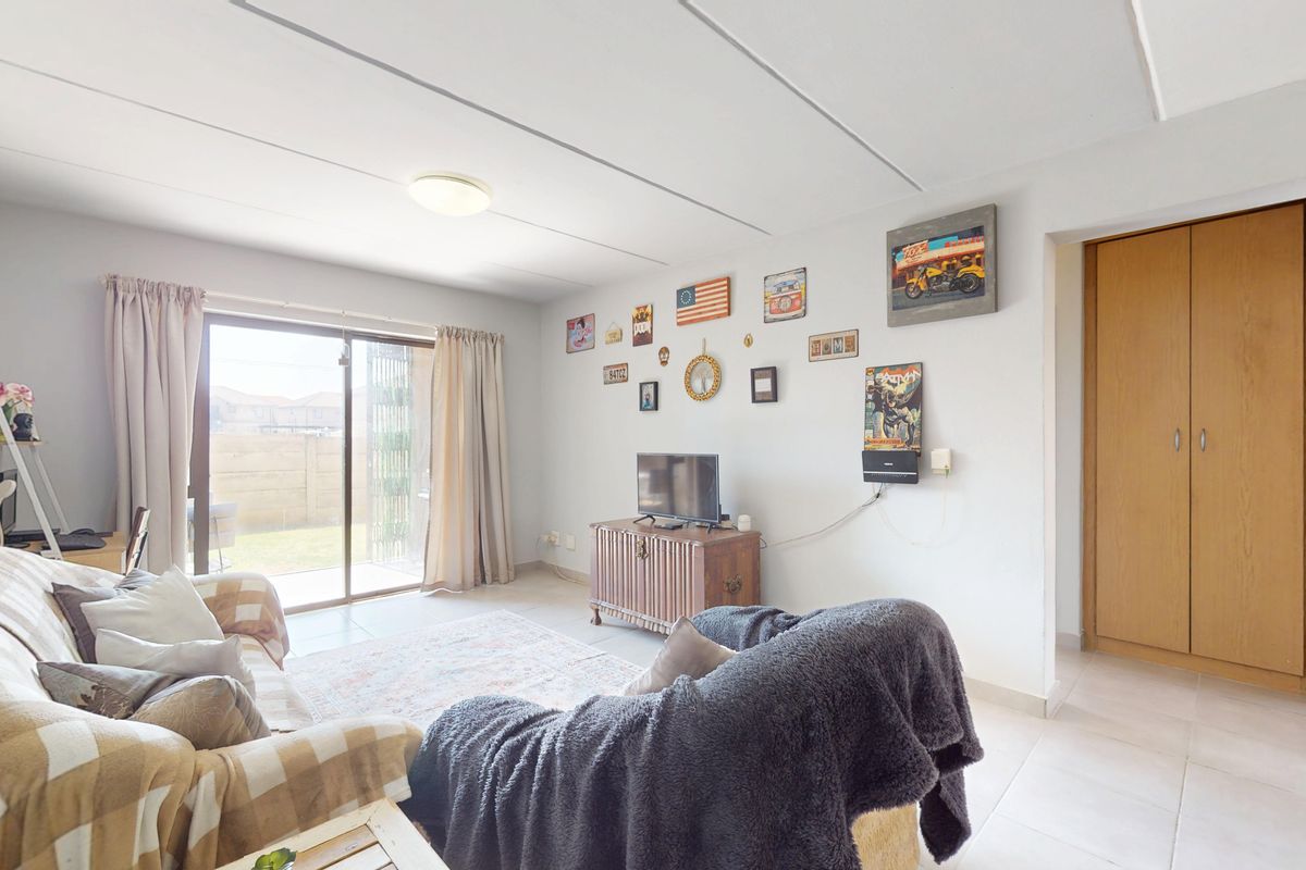 A bright living room featuring tiled flooring, a sliding glass door leading to the exterior, and a built-in storage cupboard.