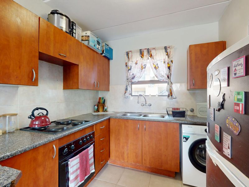 A functional kitchen featuring wood-look cabinetry, granite-style laminate countertops, a double basin sink, and a built-in electric oven and hob.