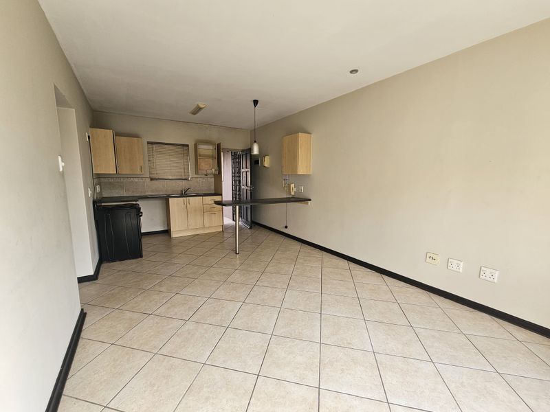 Open plan living and kitchen area featuring tiled flooring, built-in cabinetry, a breakfast bar, and direct access to a secure entrance.