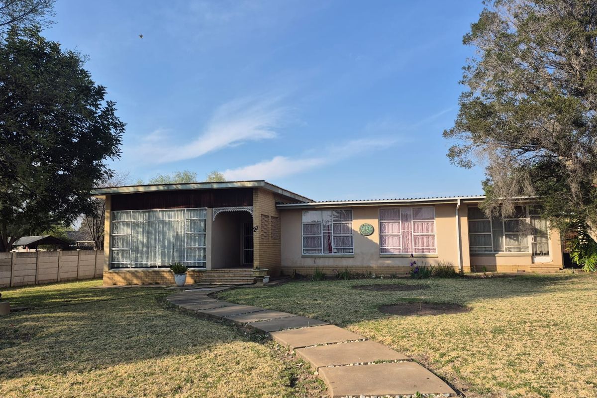 Front view of a single-story brick house featuring a concrete walkway, large windows, and a spacious front garden area.