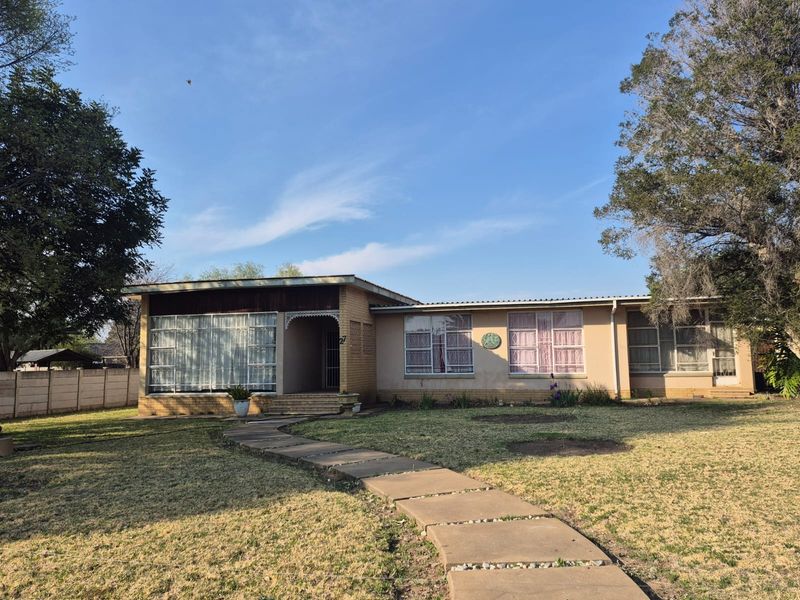 Front view of a single-story brick house featuring a concrete walkway, large windows, and a spacious front garden area.