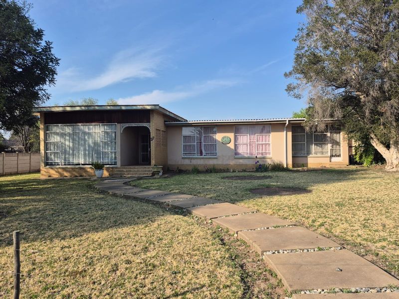 Front elevation of a single-story brick house featuring a concrete pathway leading to a covered entrance porch and large metal-framed windows.