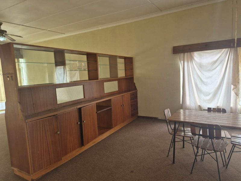 A dining area featuring a coved ceiling, ceiling fan, and carpeted flooring, offering a dated space ready for modernization.