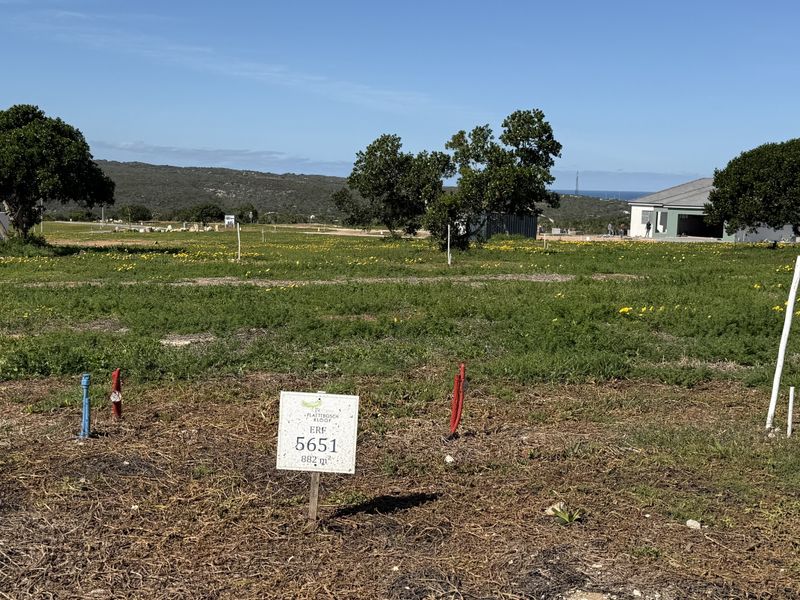 A vacant residential plot of land featuring utility connection points and boundary markers, ready for development in a coastal estate setting.