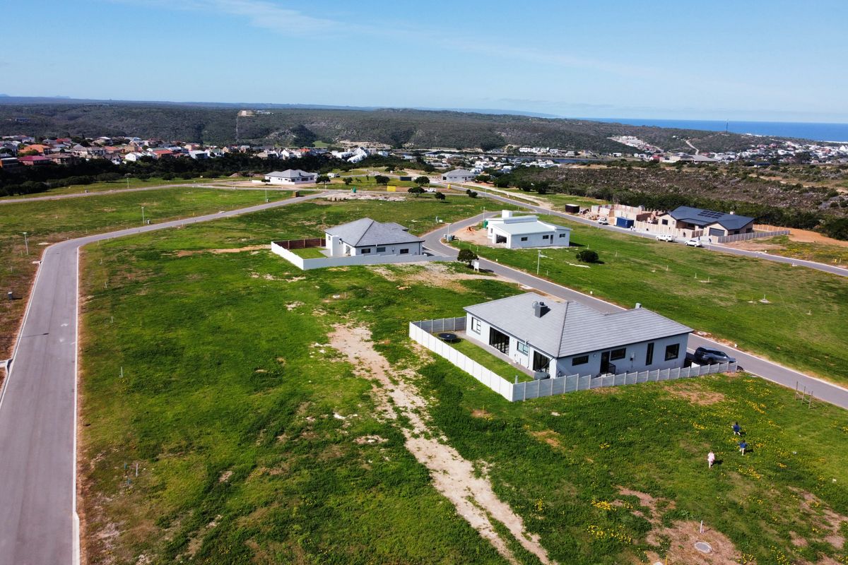 Aerial view of a residential development area featuring paved roads, established plots, and surrounding coastal landscape.
