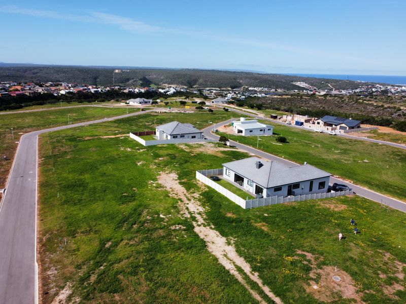 Aerial view of a residential development area featuring paved roads, established plots, and surrounding coastal landscape.
