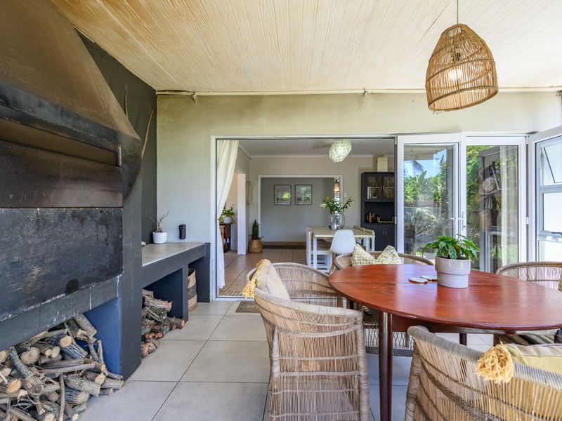 Covered patio area featuring a built-in braai, tiled flooring, and timber ceiling, with seamless access to the interior living space through bi-fold doors.