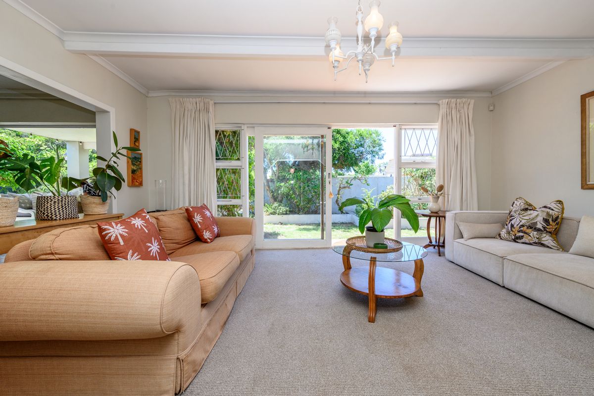Spacious living room featuring carpeted flooring, a coved ceiling with chandelier, and large sliding glass doors providing direct access to the rear garden.