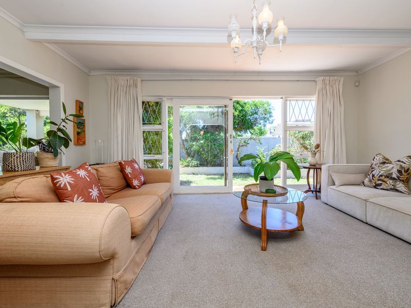 Spacious living room featuring carpeted flooring, a coved ceiling with chandelier, and large sliding glass doors providing direct access to the rear garden.