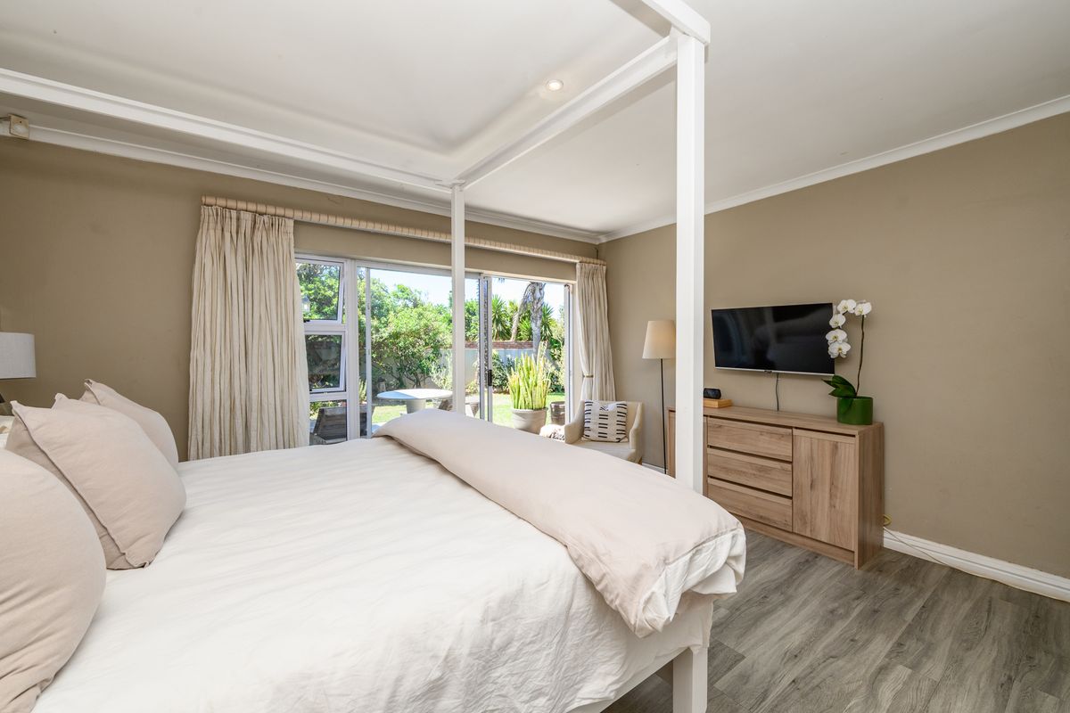 Spacious bedroom featuring modern laminate flooring, recessed lighting, and large sliding glass doors providing direct access to the rear garden.