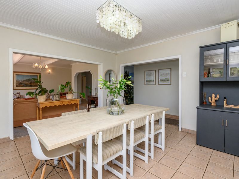 A bright dining room featuring tiled flooring, a beadboard ceiling, and built-in cabinetry, with an open-plan flow into the adjacent living area.