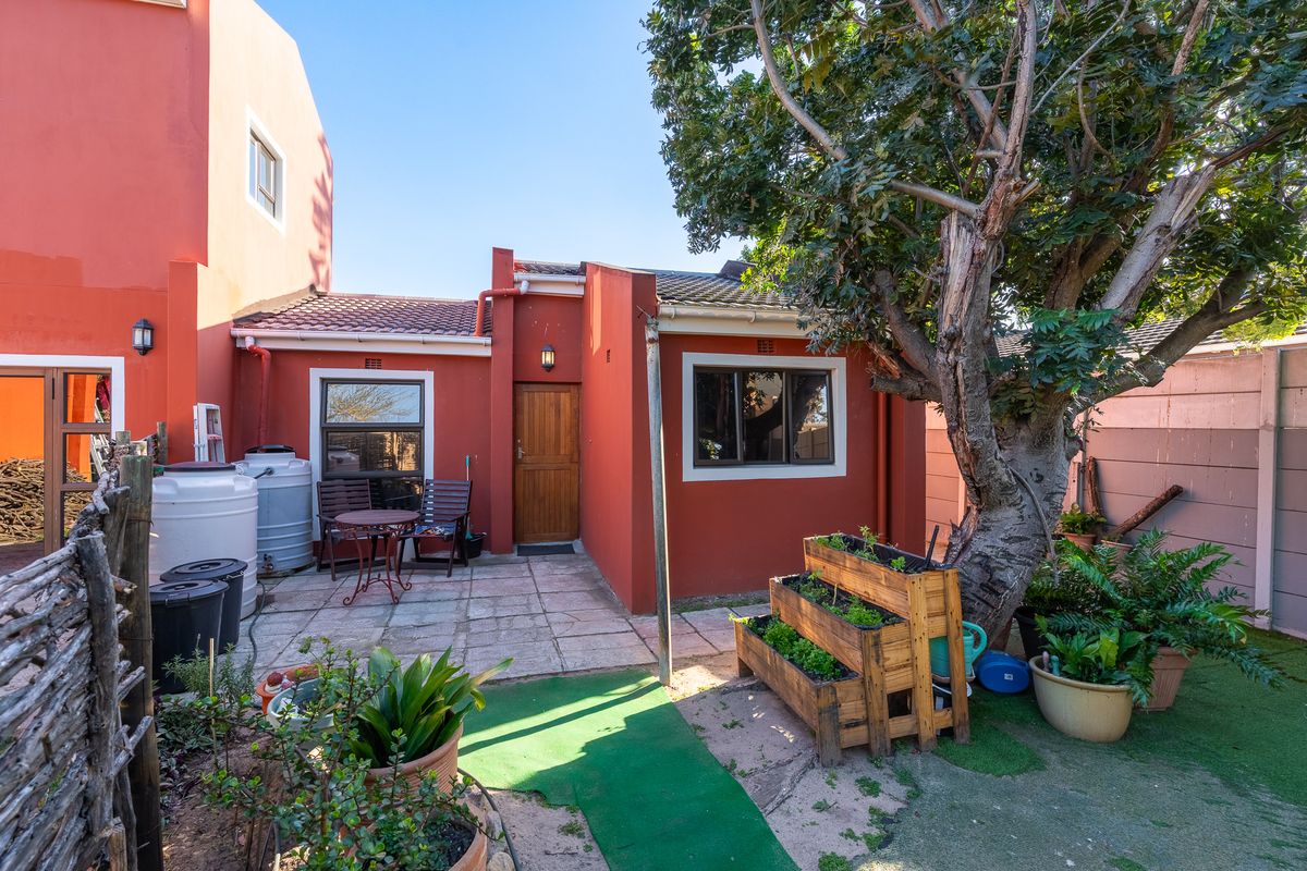 Rear exterior view featuring a paved patio area, mature tree, and access to the home via a timber door.
