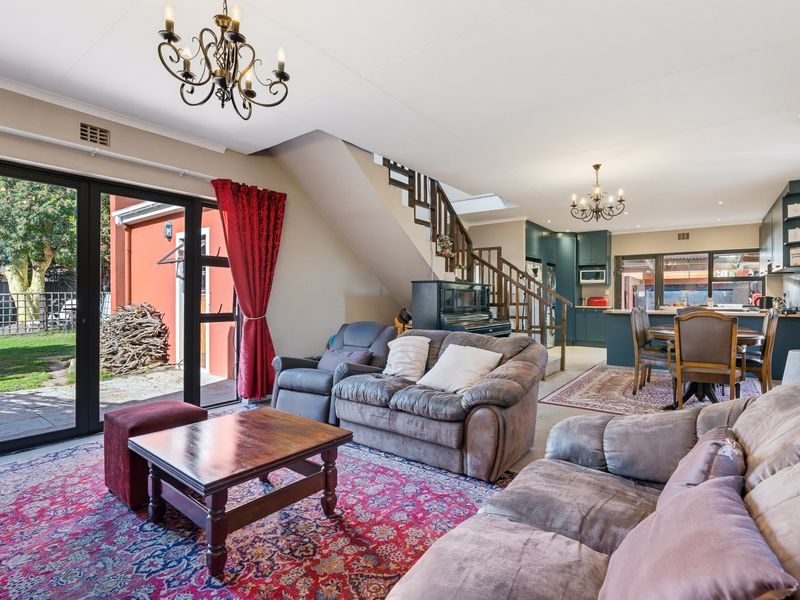 Spacious open-plan living and dining area featuring a staircase, modern kitchen cabinetry, and large sliding doors opening to the rear garden.