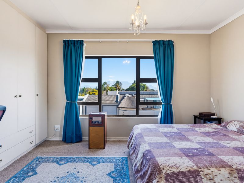A well-lit bedroom featuring built-in wardrobes, carpeted flooring, and a large window offering scenic neighbourhood views.