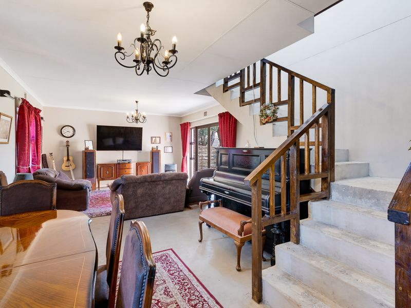 Open plan living and dining area featuring a central staircase with wooden balustrade and access to the outdoor area via sliding glass doors.