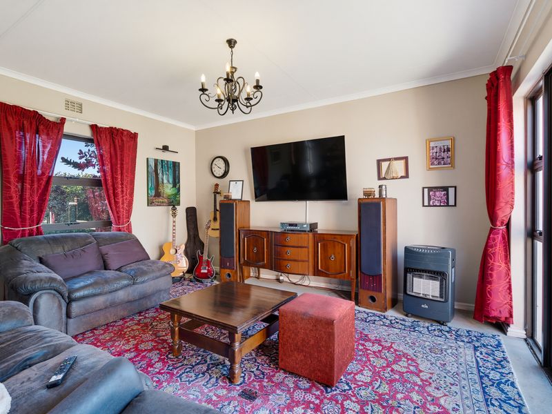 A comfortable living room featuring a chandelier, coving, and large sliding glass doors that provide access to the exterior.