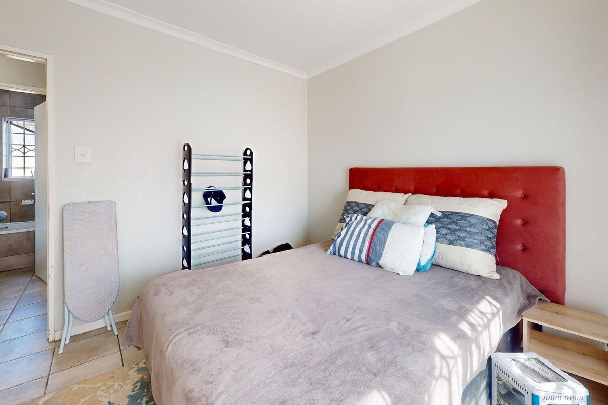 A bedroom featuring neutral walls, tiled flooring, and an adjoining en-suite bathroom with a bathtub.
