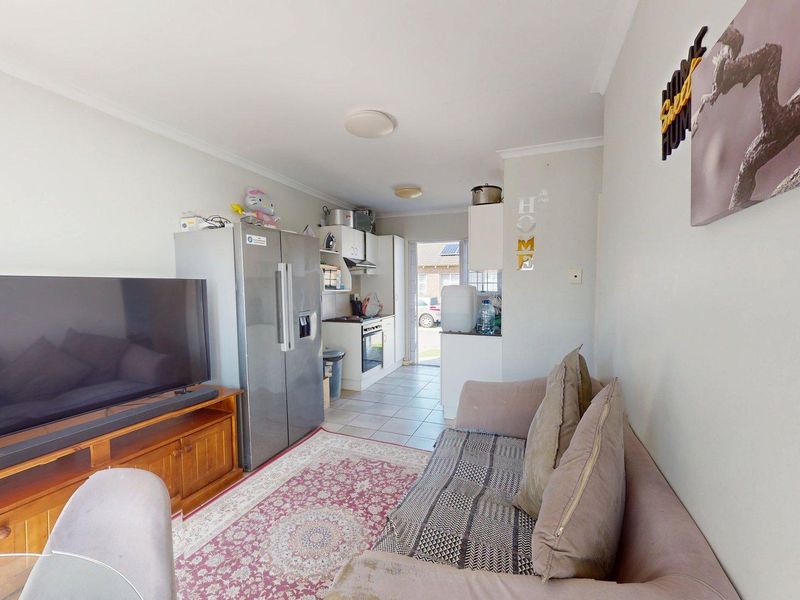 Open-plan living area featuring a compact kitchen with built-in cabinetry, oven, and hob, leading directly to the exterior entrance.