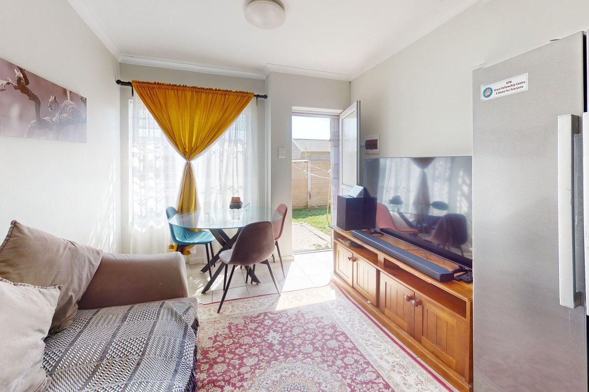 A compact living area featuring a door providing direct access to the rear garden, with neutral walls and natural light.