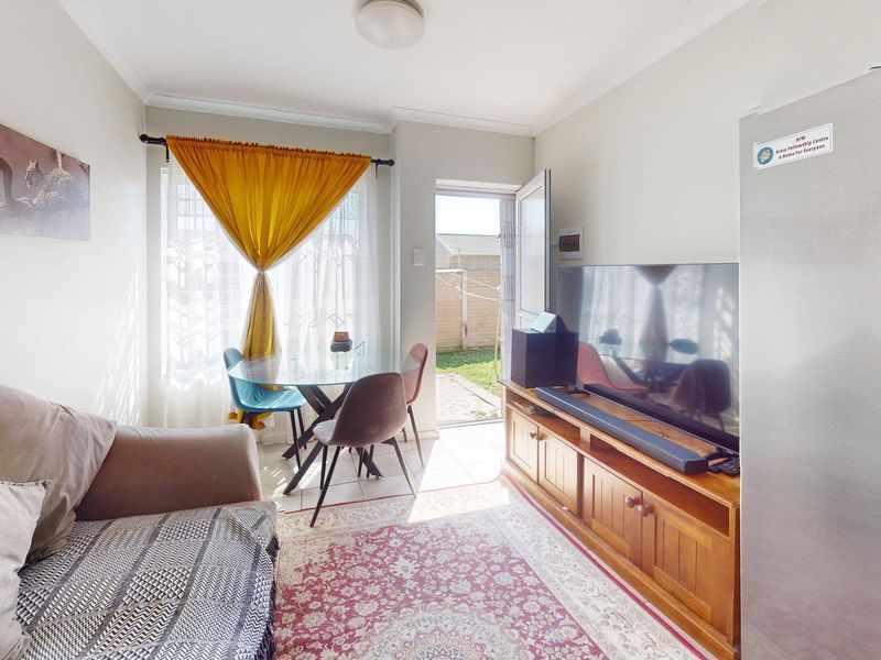 A compact living area featuring a door providing direct access to the rear garden, with neutral walls and natural light.
