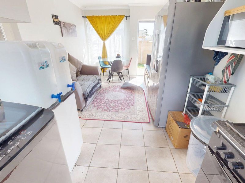 Open-plan kitchen and living area featuring tiled flooring, built-in cooking appliances, and direct access to the outdoor space through a sliding door.