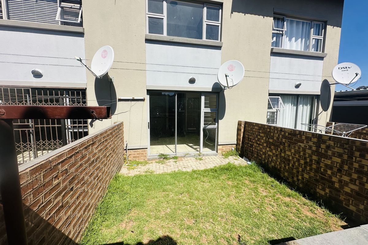 Rear view of the flat featuring a small private garden, paved patio area, and sliding door access to the interior living space.