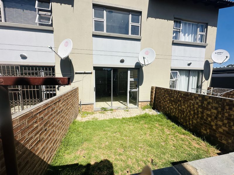 Rear view of the flat featuring a small private garden, paved patio area, and sliding door access to the interior living space.