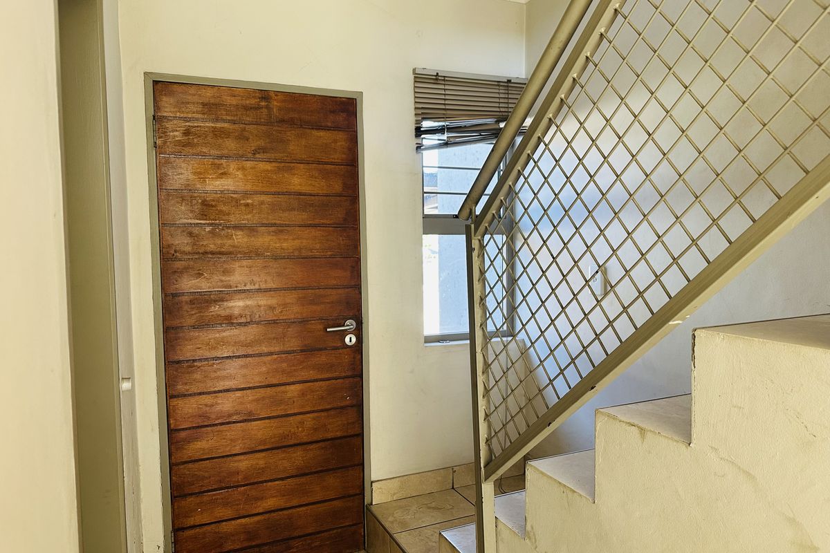 An entry area featuring a timber door, tiled flooring, and a metal staircase railing leading to the upper level.