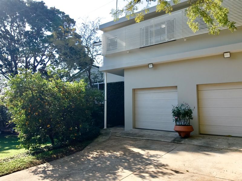 Front elevation featuring a double garage with a concrete driveway and modern slatted architectural detailing on the upper level.