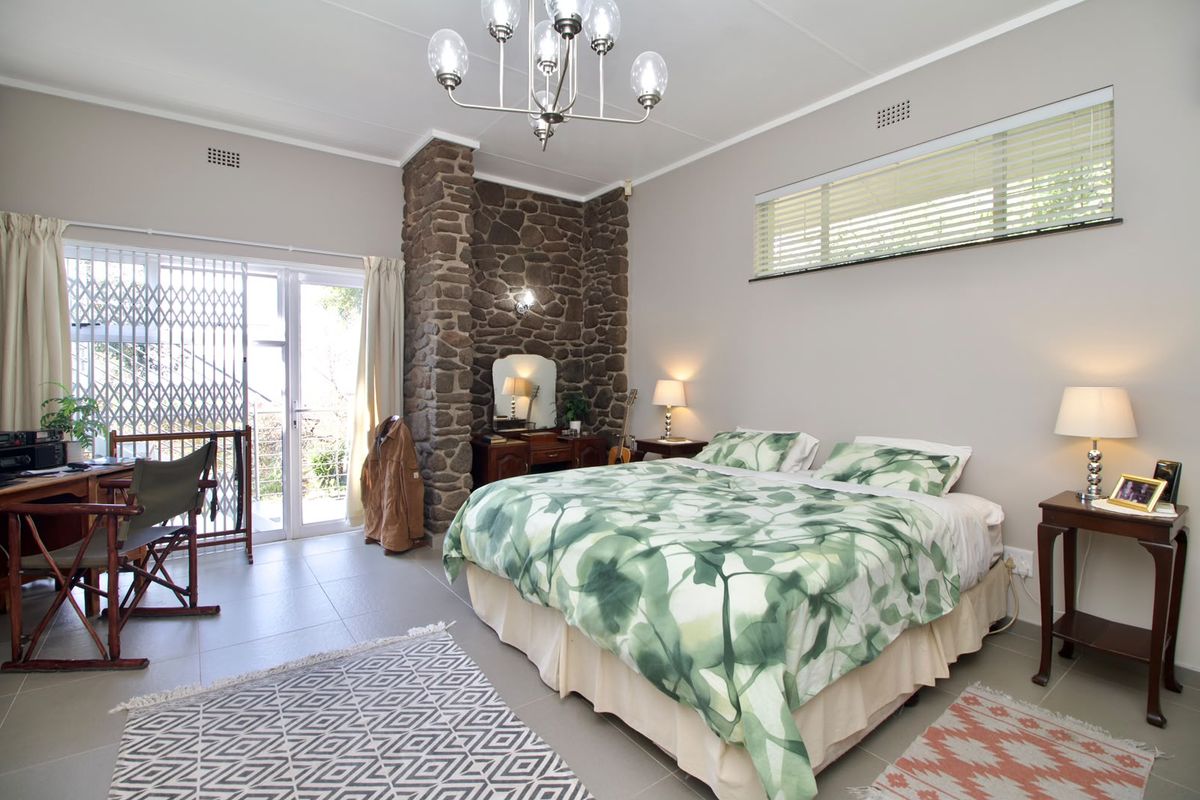 Spacious bedroom featuring a distinctive stone accent wall, tiled flooring, and direct access to an outdoor area through a sliding glass door.