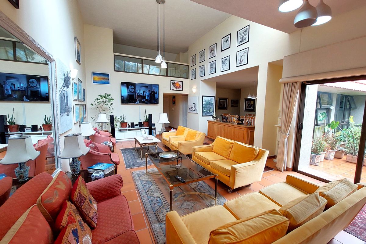 Spacious double-volume living room featuring terracotta floor tiles, abundant natural light, and direct access to an outdoor patio area.