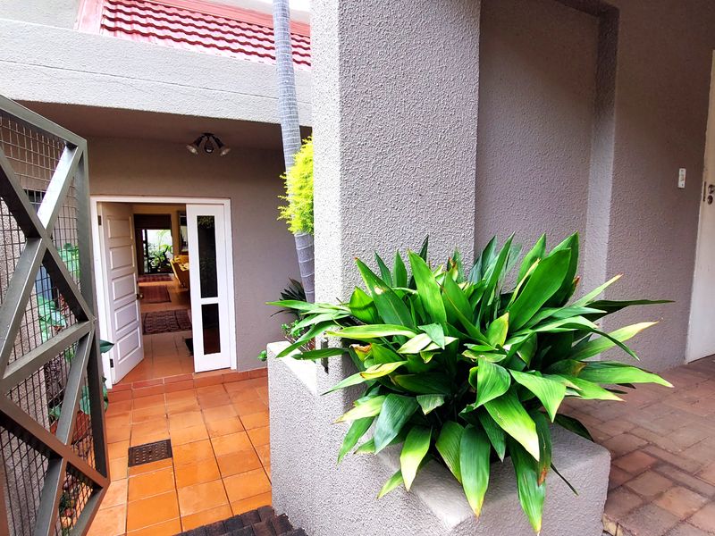A welcoming townhouse entrance featuring a secure gate, tiled patio area, and textured exterior walls leading into the main living space.