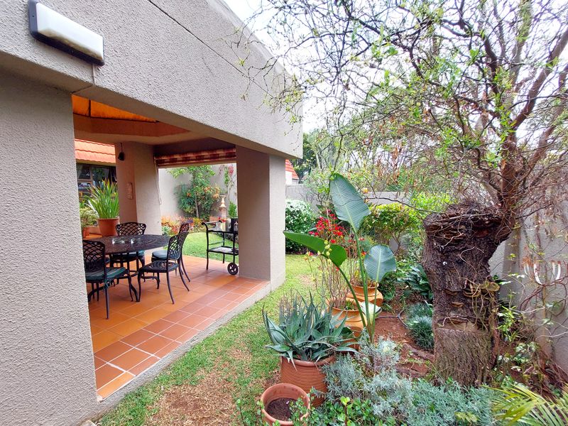 A covered patio area with tiled flooring, providing a seamless transition to the surrounding garden space.