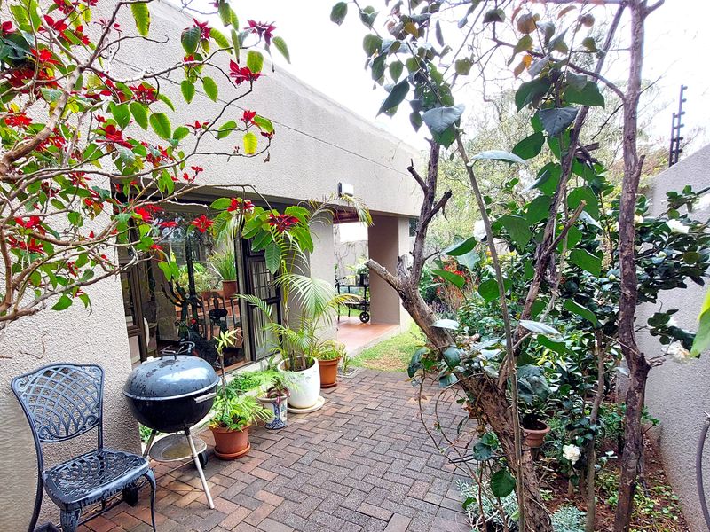 A private paved patio area featuring a covered veranda section and direct access to the interior through sliding glass doors.