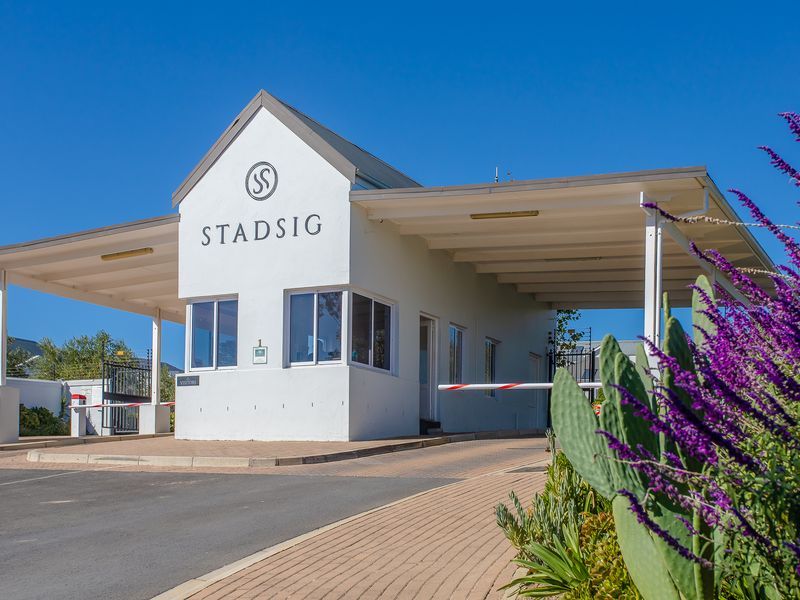 The main entrance gatehouse for Stadsig estate, featuring a secure boom gate, paved driveway, and well-maintained exterior structure.