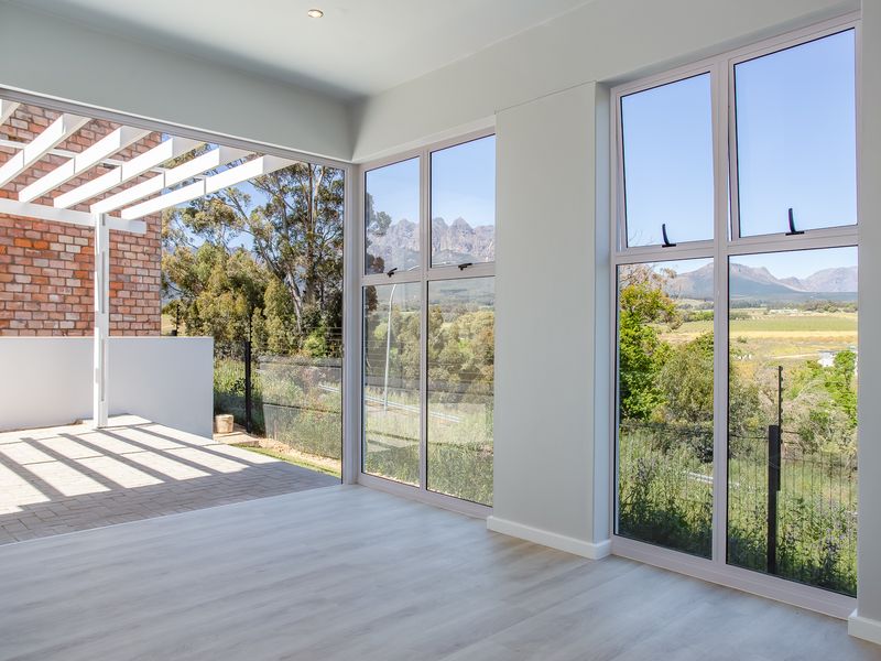 Bright and spacious living area featuring large windows with scenic mountain views and direct access to a covered patio with a pergola.